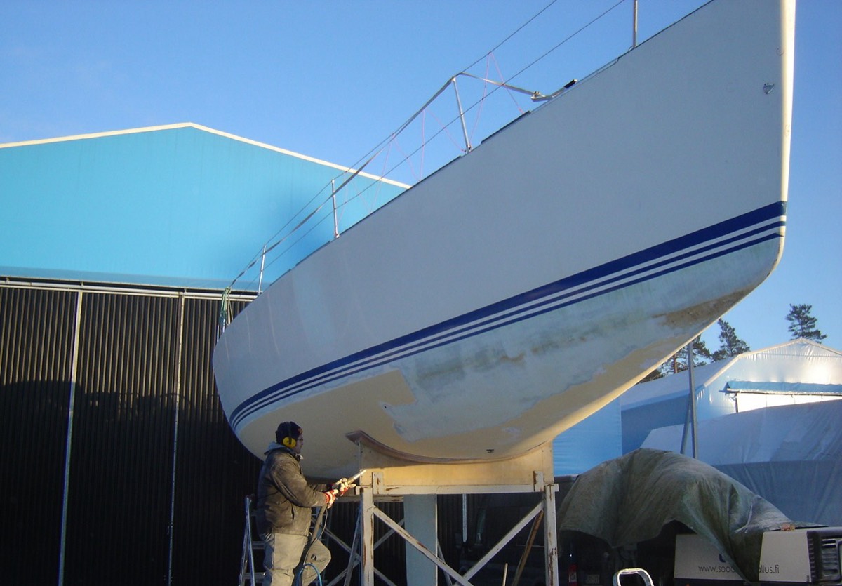 Boat hull being abrasive-blasted in a yard