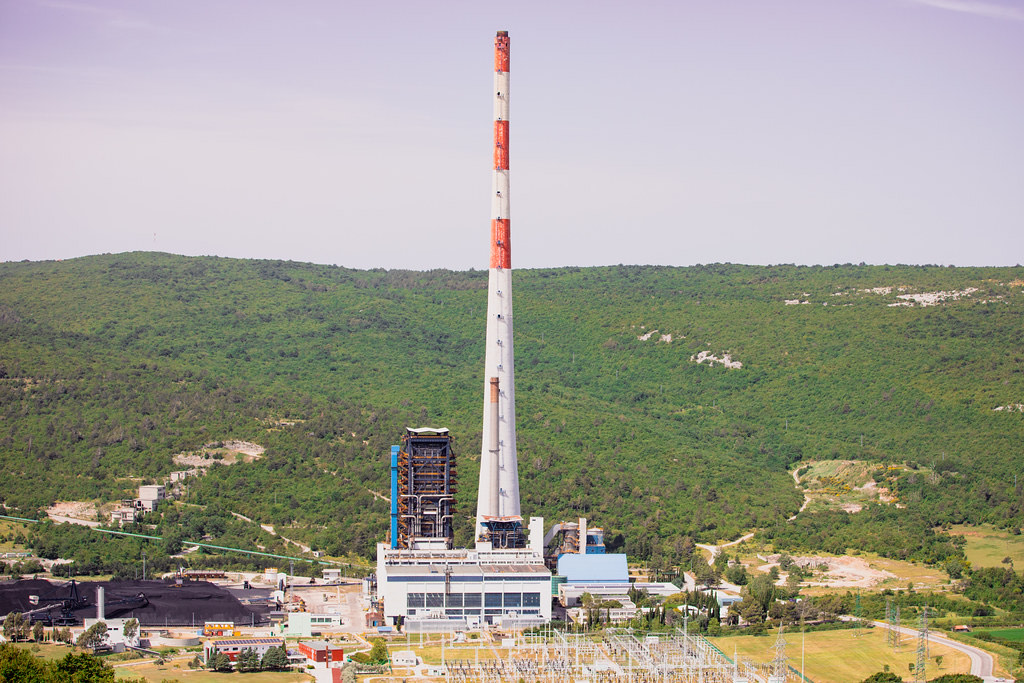 Thermal power plant with a tall chimney in a green valley